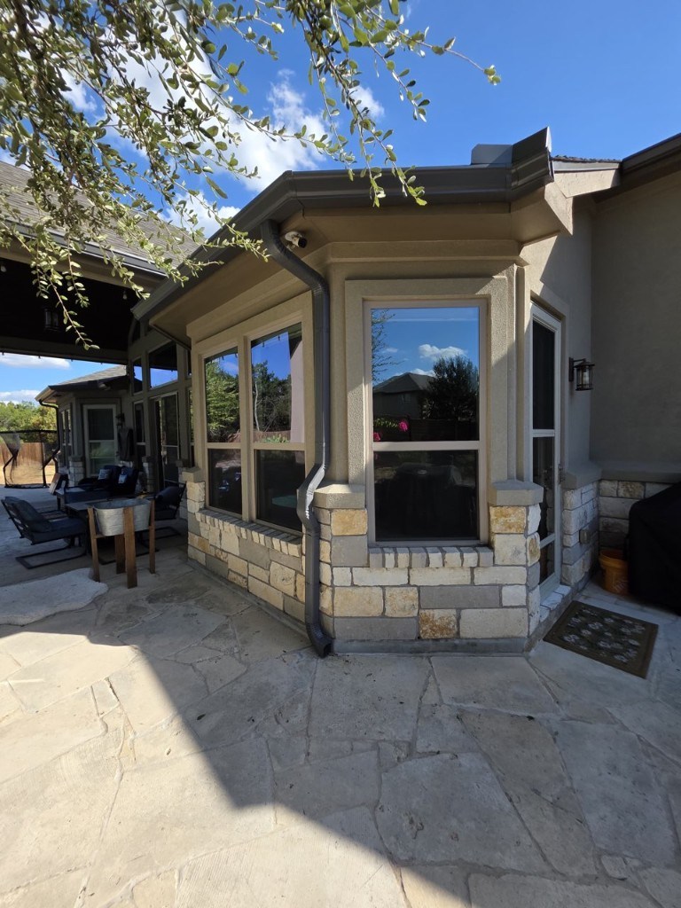 Downspout on a stone bay window beside a covered patio in New Braunfels